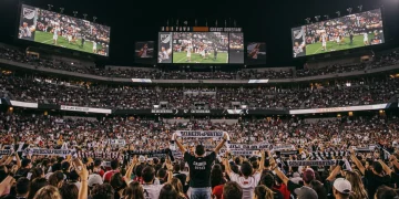 MLS stadium filled with fans, digital screens, and merchandise, symbolizing enhanced fan engagement.
