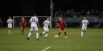MLS scout observing a collegiate soccer match, evaluating potential 2025 SuperDraft prospects.