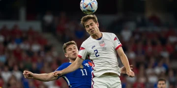 US center-back winning an aerial duel in a soccer match